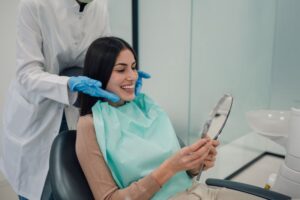 Happy dental patient looking in mirror after cosmetic treatments 